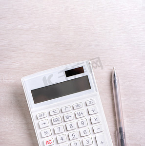 财务分析表格摄影照片_明亮木桌上的白色计算器和笔、财务利润分析和统计、投资风险概念、复制空间、顶视图平躺