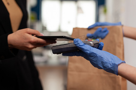 POS摄影照片_使用 POS 的智能手机支付外卖食品午餐订单的女商人特写