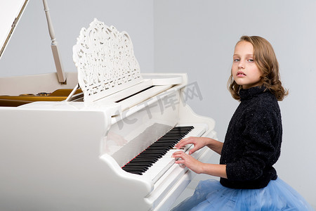 弹大钢琴的美丽的十几岁的女孩