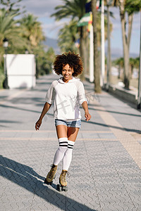 3d溜溜摄影照片_穿着旱冰鞋的黑人妇女在棕榈树的海滨长廊溜旱冰