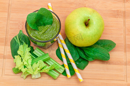 玻璃烧杯摄影照片_玻璃烧杯中苹果、芹菜和菠菜的新鲜绿色冰沙