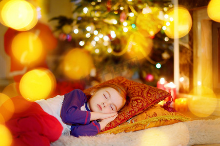 睡觉小女孩摄影照片_睡在圣诞树下的小女孩