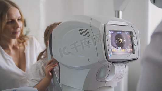 小孩眼睛摄影照片_眼科医生房间里的母女 — 诊所的验光师检查小孩的视力