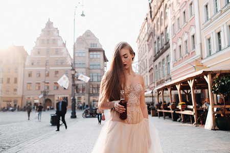弗罗茨瓦夫老城，一位身着长发婚纱、手拿饮料瓶的新娘。