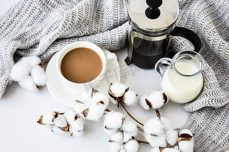 French Press 咖啡和牛奶放在毛衣背景的白色桌子上。
