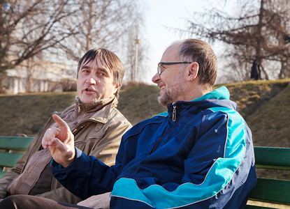 老人聊天摄影照片_两个年长的男人在公园的长椅上聊天