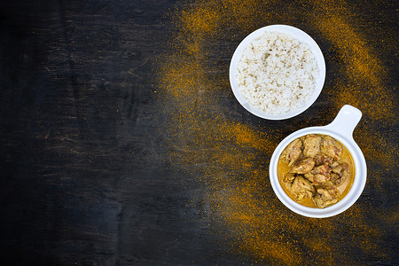 选择样式摄影照片_深色背景上的简单白盘中的橙辣鸡肉咖喱和米饭。