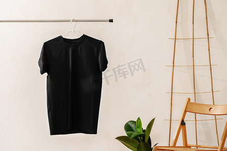衣架上的纯黑色棉质 T 恤，适合您的设计