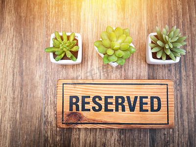 桌牌摄影照片_餐厅木桌上的木制预留标志，餐厅预订座位，用于庆祝日概念约会。