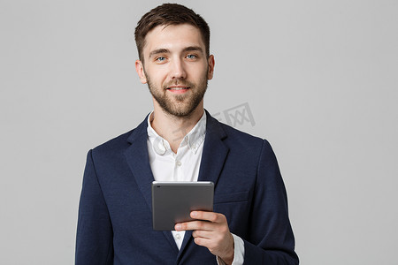 经营理念-肖像英俊的商人玩数字平板电脑与自信的笑脸。