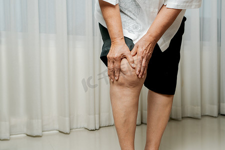 膝盖疼痛摄影照片_在家遭受膝盖疼痛的老年妇女，健康问题概念