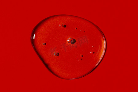清晰透明的液体凝胶滴或涂片隔离在鲜艳的红色背景上。