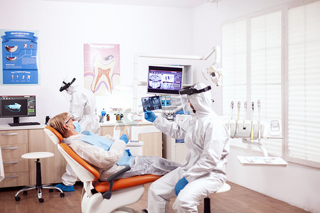 放射防护摄影照片_牙医穿着防护服 agasint coroanvirus 拿着病人 x 光片