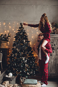 妻子和丈夫在家里穿着同款睡衣装饰圣诞树