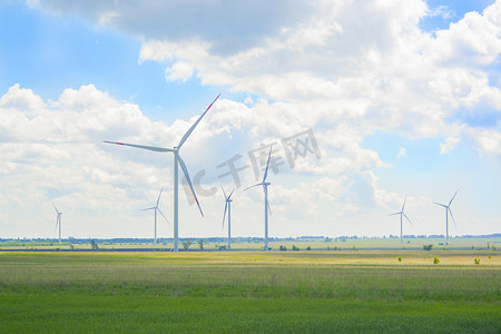 阳光明媚的日子里，绿色田野上有许多又大又高的风车。