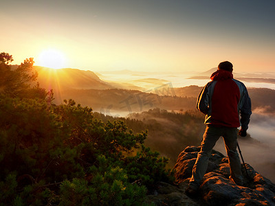 快乐的摄影爱好者享受悬崖上大自然秋日黎明的摄影