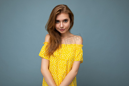年轻美丽的深色金发女郎带着真挚的情感被隔离在背景墙上，复制空间穿着时尚的夏季黄色连衣裙。