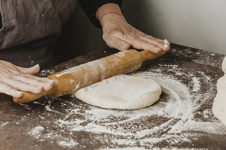 厨师女厨师摄影照片_女厨师使用擀面杖披萨面团。