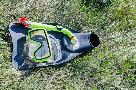 通气管摄影照片_水下面罩、通气管和脚蹼躺在草地上。