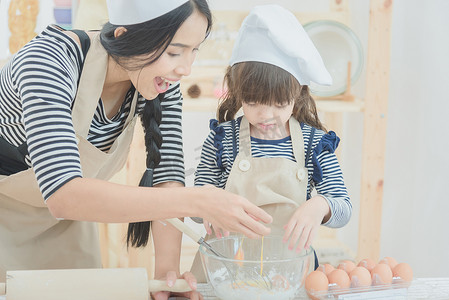 幸福的家庭母亲和她的女儿一起做饭，在厨房里做蛋糕