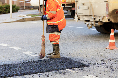 道路建设者在部分道路上收集新鲜沥青，并将其平整，以便在道路建设中进行修复。