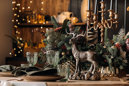 圣诞餐桌装饰、上菜前戴眼镜的宴会桌、带季节性装饰的圣诞餐桌特写、水晶玻璃和装饰鹿
