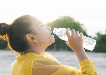 亚洲妇女用光塑料瓶喝纯净水