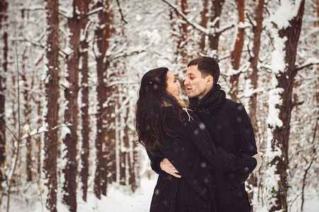 一个穿着暖和的衣服和围巾的男孩和女孩在雪天散步