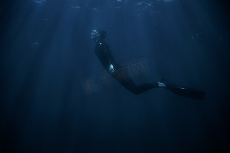 男子穿着潜水服在水下浮潜。