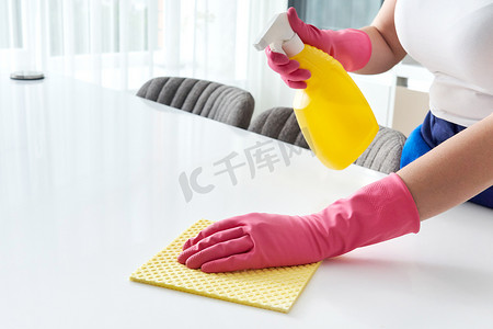 表面摄影照片_用毛巾和手套用消毒喷雾瓶清洗表面清洁家庭餐桌消毒厨房餐桌表面。 