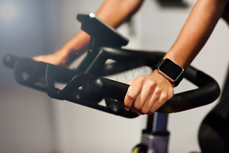 立体动感摄影照片_在健身房里用智能手表在室内做动感单车或单车运动的女性