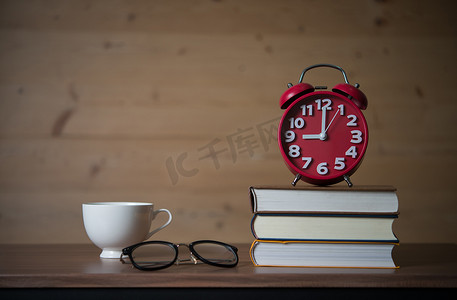 上午 9 点闹钟在一堆书上，戴着眼镜和一杯 c