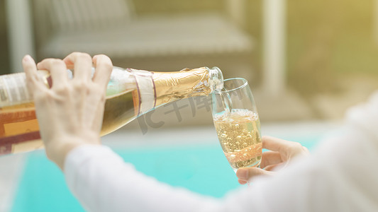 女人手将香槟倒入玻璃杯中。