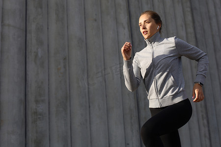 年轻迷人的运动健身女性在城市的日落或日出时在户外锻炼时跑步