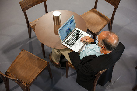 坐在桌边使用笔记本电脑工作的男人的顶视图
