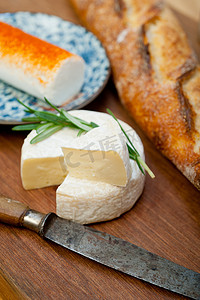 创意面包摄影照片_切木机上的法式奶酪和新鲜法式长棍面包