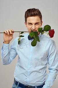 浪漫系摄影照片_浪漫的男人，一朵红玫瑰，穿着蓝色衬衫，脖子上系着领结，灰色背景