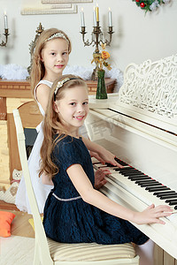 弹钢琴孩子摄影照片_双胞胎女孩弹钢琴。