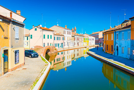 科马基奥 - 2016 年 10 月，意大利艾米利亚罗马涅：运河景观，桥梁和彩色房屋倒映在水中。