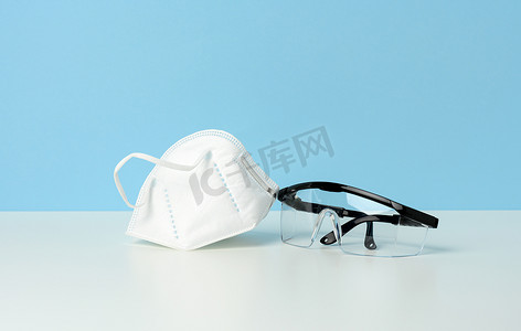 蓝色背景透明塑料防护医用眼镜和白色一次性口罩