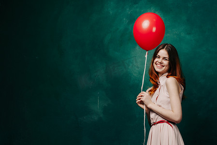 带着红色气球绿色背景假期的快乐女人