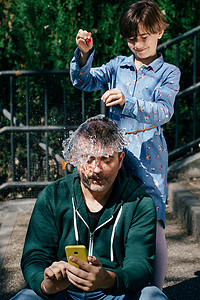 女孩在父亲的头上吹起一个装满水的气球