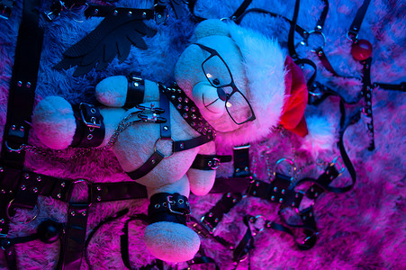 戴着圣诞老人帽子的玩具熊是霓虹灯下 BDSM 游戏的圣诞礼物