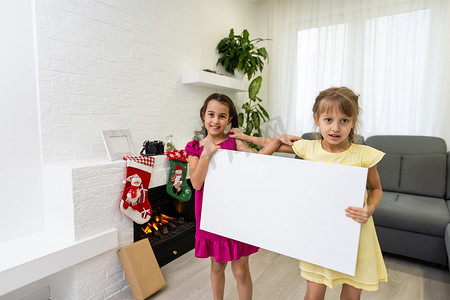 圣诞孩子手里拿着空的横横幅站着，两个小女孩拿着画布
