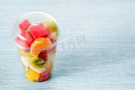 蓝色背景塑料杯中的鲜切水果