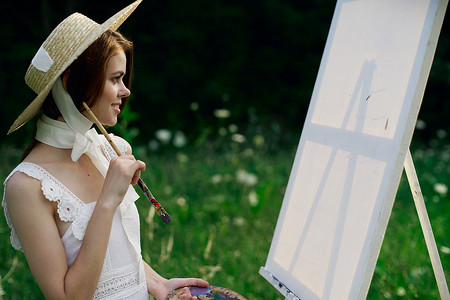 白裙摄影照片_穿白裙的女人在自然画架上画一幅画