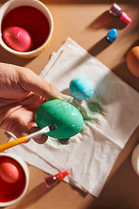 彩绘人手摄影照片_假期、传统和人的概念 — 人手用刷子给复活节彩蛋上色的特写