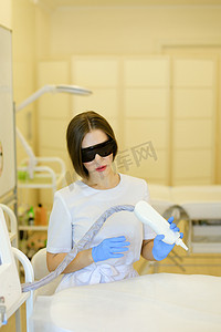 戴着特殊用途眼镜和乳胶手套的白人美容师坐在永久化妆设备附近。