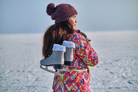 在结冰的湖面上滑雪后，一名妇女将冰鞋扛在肩上