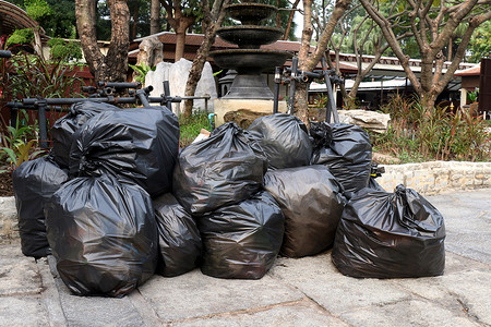 垃圾堆垃圾黑袋塑料堆在地面公共公园，许多倾倒黑色垃圾塑料袋堆